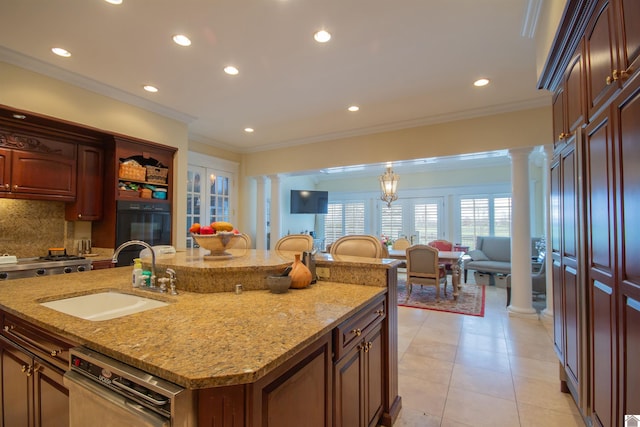 kitchen with an island with sink, tasteful backsplash, sink, and ornate columns