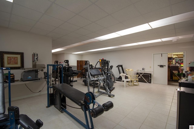 workout area featuring a drop ceiling and light tile floors