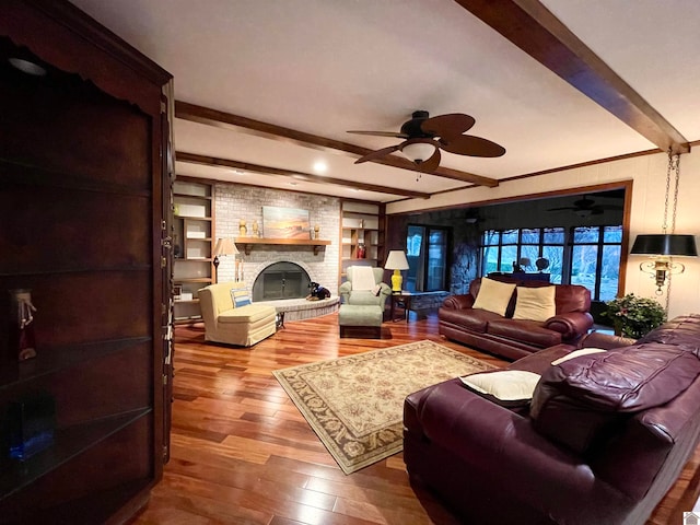 living room featuring hardwood / wood-style floors, beamed ceiling, ceiling fan, and a fireplace