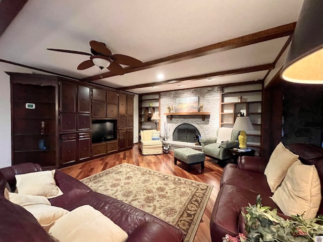 living room with brick wall, wood-type flooring, ceiling fan, and a brick fireplace