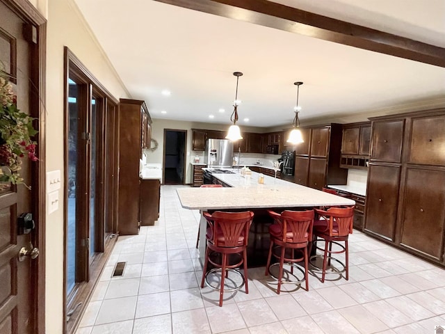 kitchen featuring a kitchen island, light tile floors, pendant lighting, light stone countertops, and stainless steel refrigerator with ice dispenser