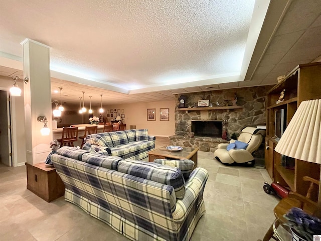 tiled living room with a textured ceiling and a stone fireplace