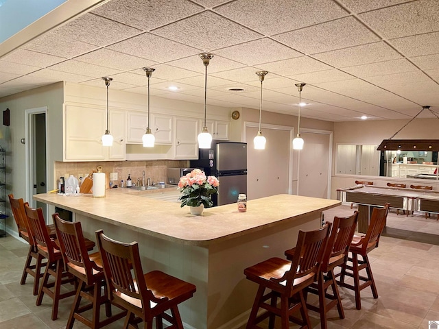 kitchen with a kitchen bar, hanging light fixtures, light tile floors, and white cabinetry