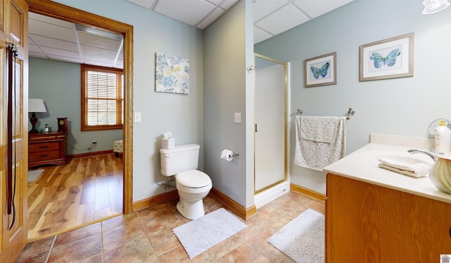 bathroom featuring toilet, a shower with door, vanity, a paneled ceiling, and tile flooring