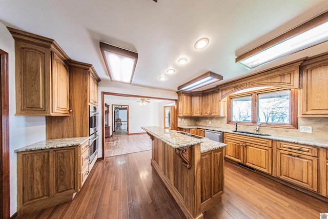 kitchen with ceiling fan, stainless steel appliances, a kitchen island, and wood-type flooring