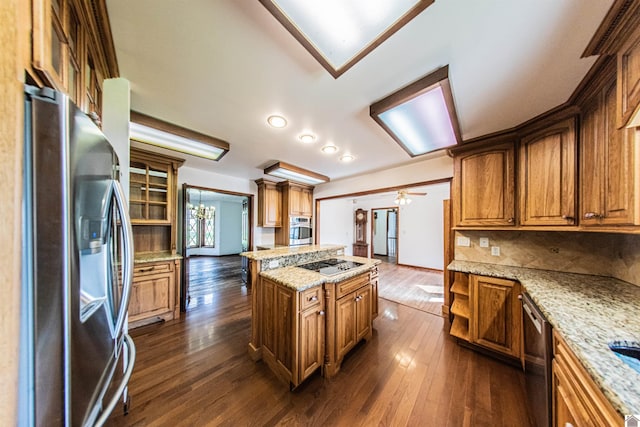 kitchen with appliances with stainless steel finishes, tasteful backsplash, light stone counters, ceiling fan, and dark hardwood / wood-style flooring