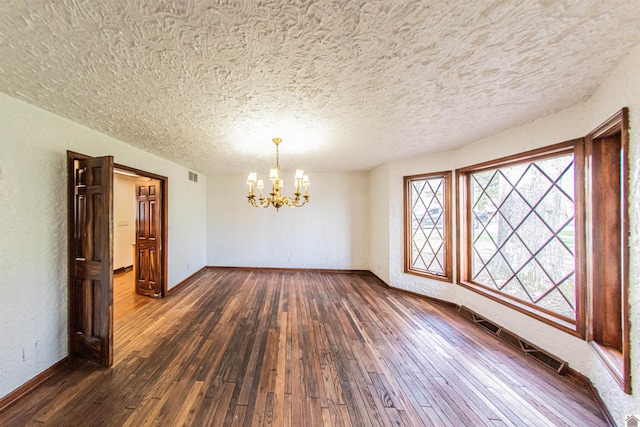 unfurnished dining area with a notable chandelier, a textured ceiling, and dark hardwood / wood-style flooring