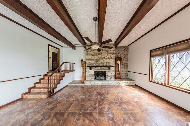 unfurnished living room featuring ceiling fan, dark tile flooring, beam ceiling, a textured ceiling, and a stone fireplace