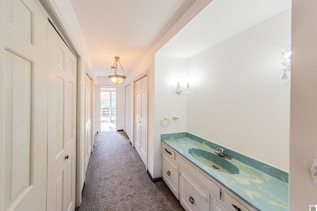 hallway with sink and dark carpet