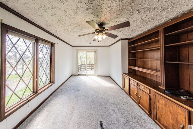 carpeted living room featuring ceiling fan, ornamental molding, and a textured ceiling