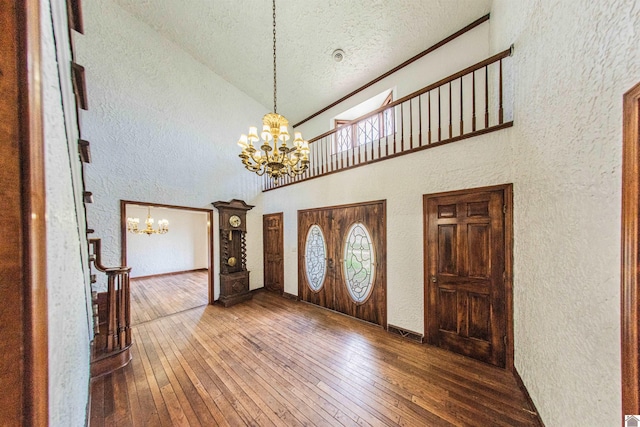 entrance foyer featuring high vaulted ceiling, an inviting chandelier, a textured ceiling, and dark wood-type flooring