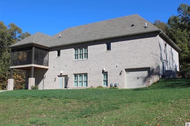 back of property featuring a sunroom, a garage, and a lawn