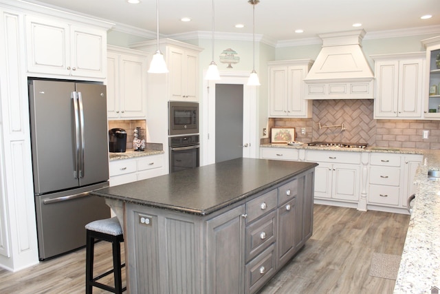 kitchen featuring backsplash, premium range hood, appliances with stainless steel finishes, and a center island