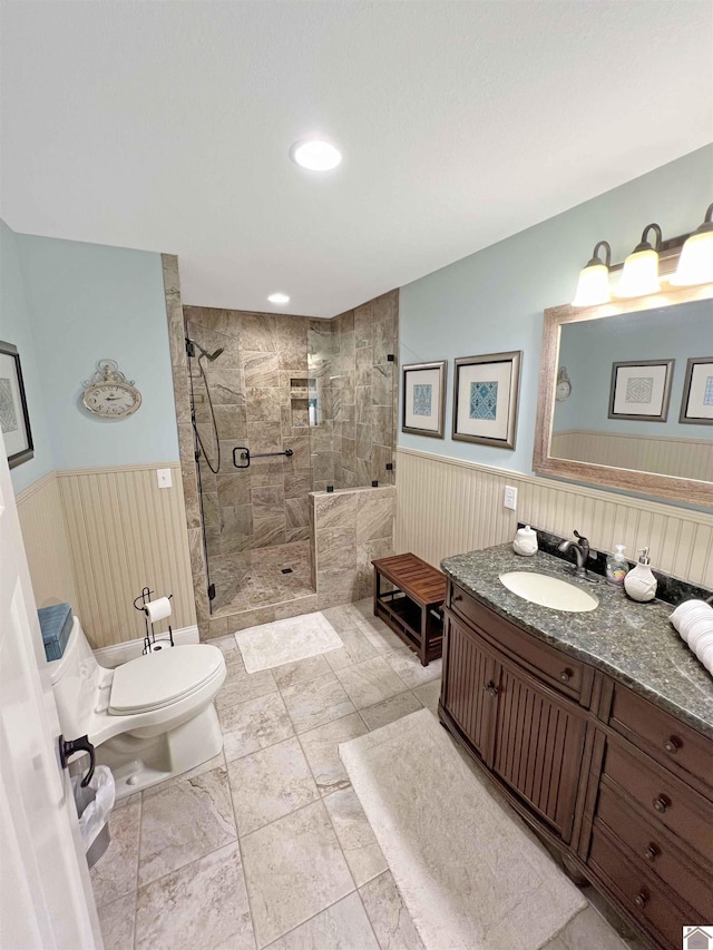 bathroom featuring tile flooring, toilet, tiled shower, and vanity