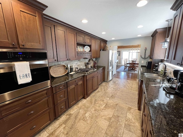 kitchen featuring appliances with stainless steel finishes, dark stone counters, tasteful backsplash, and sink