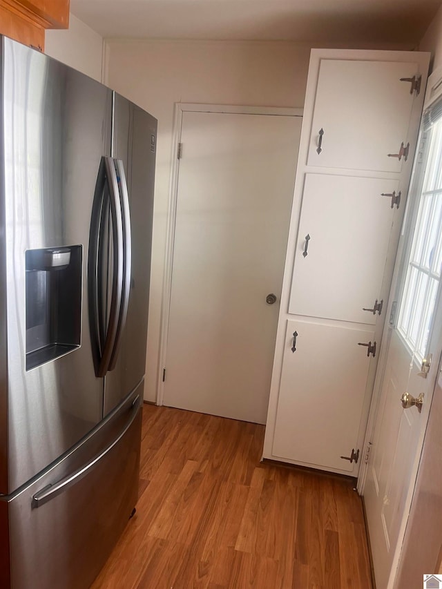 kitchen featuring stainless steel refrigerator with ice dispenser, light wood-type flooring, and white cabinetry