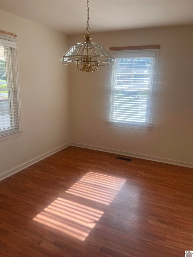 empty room featuring a chandelier and dark hardwood / wood-style floors