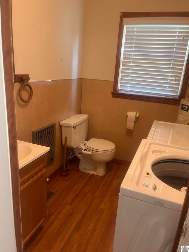 bathroom with toilet, washer / clothes dryer, and hardwood / wood-style floors