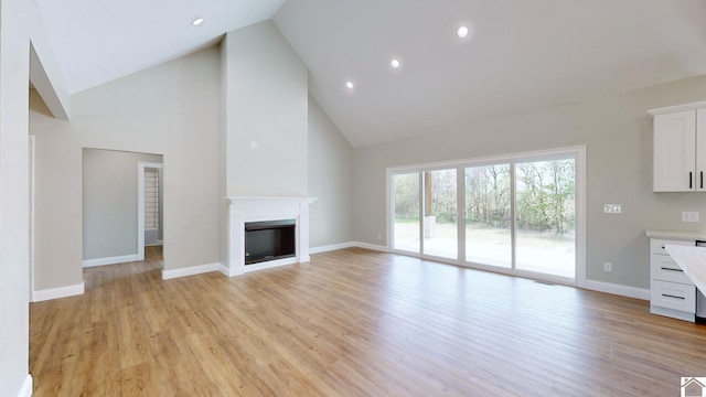 unfurnished living room featuring high vaulted ceiling and light hardwood / wood-style floors