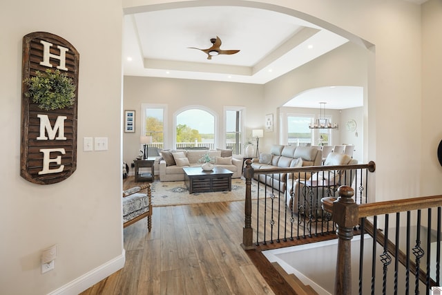 corridor featuring a wealth of natural light, a tray ceiling, hardwood / wood-style flooring, and a chandelier