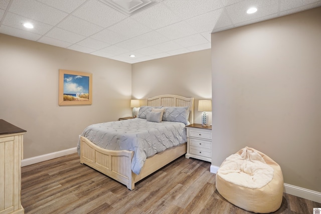 bedroom featuring a drop ceiling and wood-type flooring