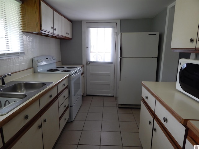 kitchen with white appliances, tasteful backsplash, white cabinets, sink, and light tile floors