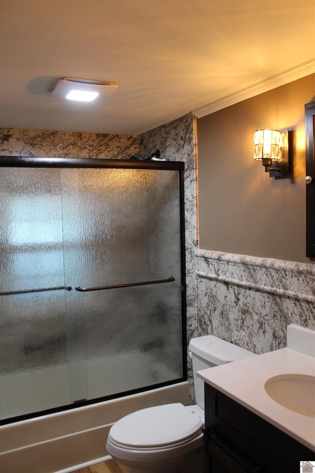 full bathroom featuring vanity, combined bath / shower with glass door, crown molding, and toilet