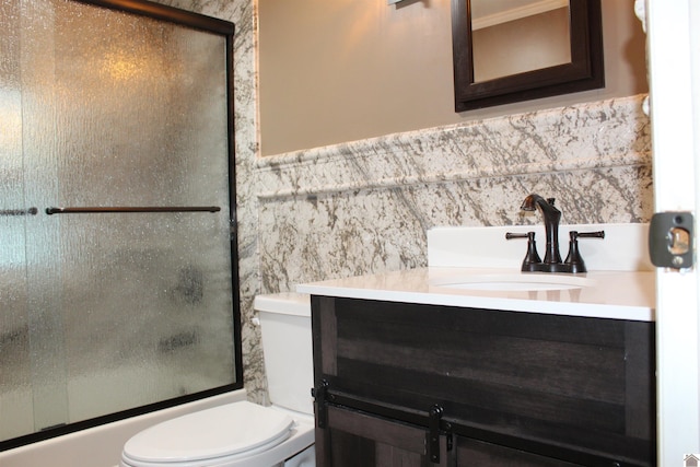 full bathroom with vanity, toilet, combined bath / shower with glass door, and tile walls