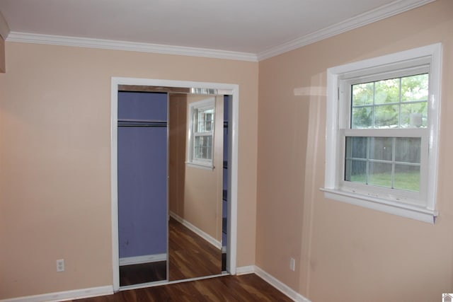 unfurnished bedroom with dark wood-type flooring, crown molding, and a closet