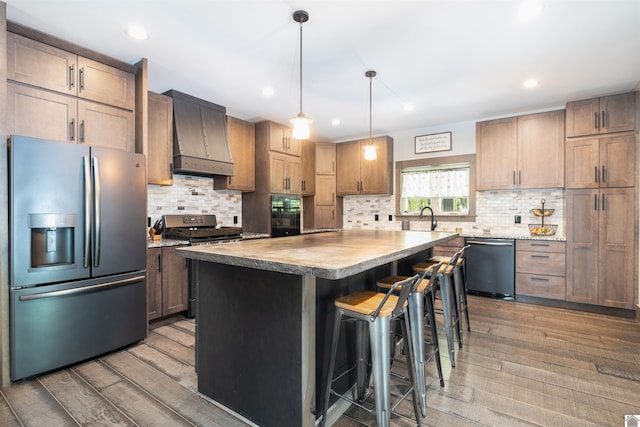 kitchen featuring appliances with stainless steel finishes, a kitchen island, tasteful backsplash, a kitchen breakfast bar, and hardwood / wood-style floors