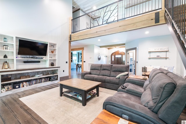 living room featuring wood-type flooring, a high ceiling, and ceiling fan