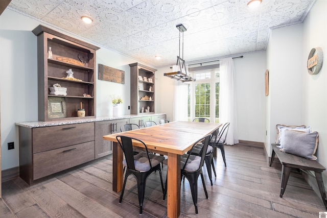 dining space with built in features, ornamental molding, and hardwood / wood-style flooring