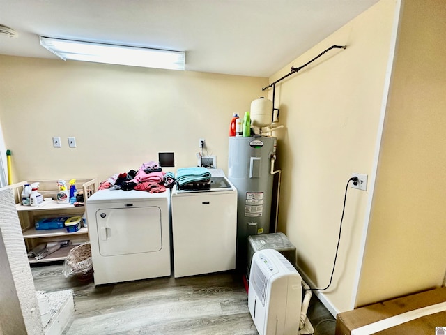 laundry area featuring washer and dryer, light wood-type flooring, and water heater