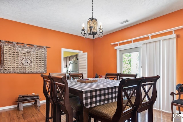 dining space featuring a chandelier, hardwood / wood-style flooring, and a textured ceiling