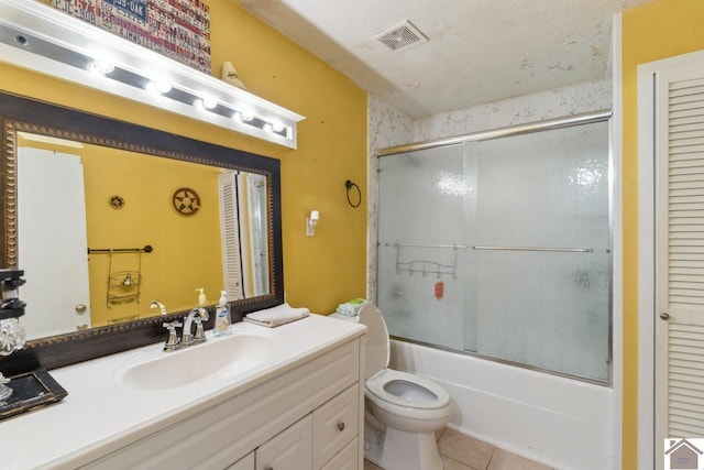 full bathroom with large vanity, enclosed tub / shower combo, tile flooring, toilet, and a textured ceiling