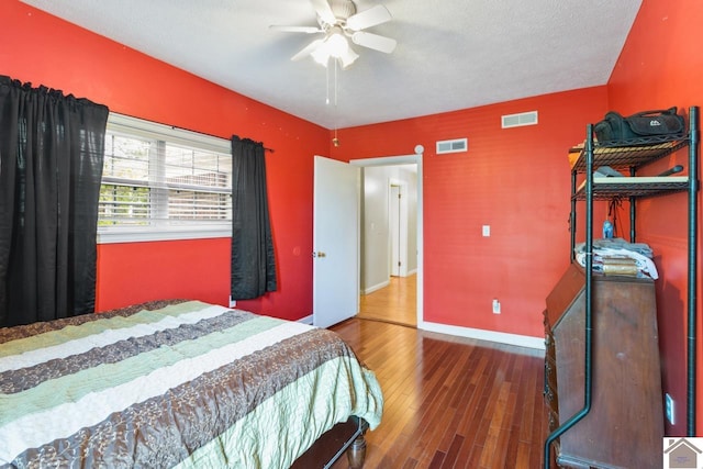 bedroom with ceiling fan, dark hardwood / wood-style floors, and a textured ceiling