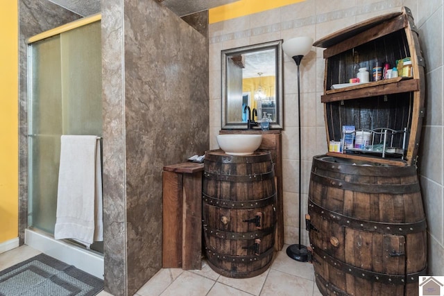 bathroom featuring tile walls, a shower with door, and tile flooring