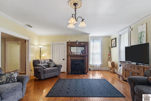 living room with crown molding, hardwood / wood-style flooring, and a chandelier