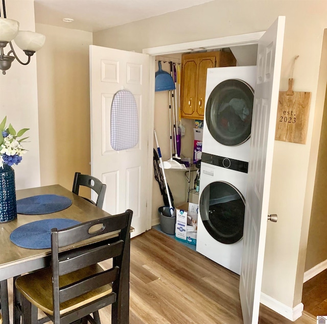 washroom with hardwood / wood-style floors and stacked washer and clothes dryer