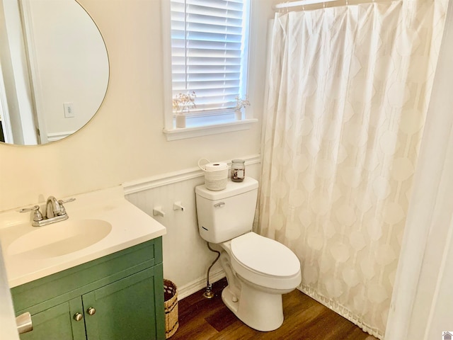 bathroom featuring hardwood / wood-style flooring, toilet, and vanity with extensive cabinet space