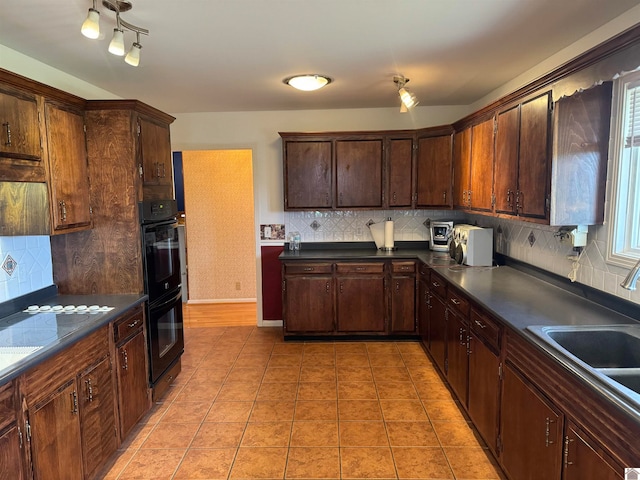 kitchen with dark brown cabinetry, tasteful backsplash, light tile floors, and black double oven