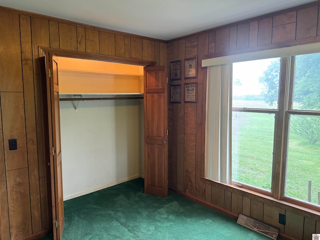 unfurnished bedroom with wooden walls, carpet floors, and multiple windows