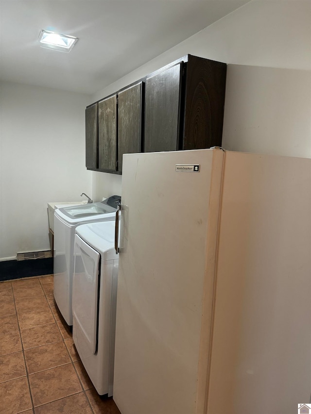 washroom with independent washer and dryer, cabinets, and light tile flooring