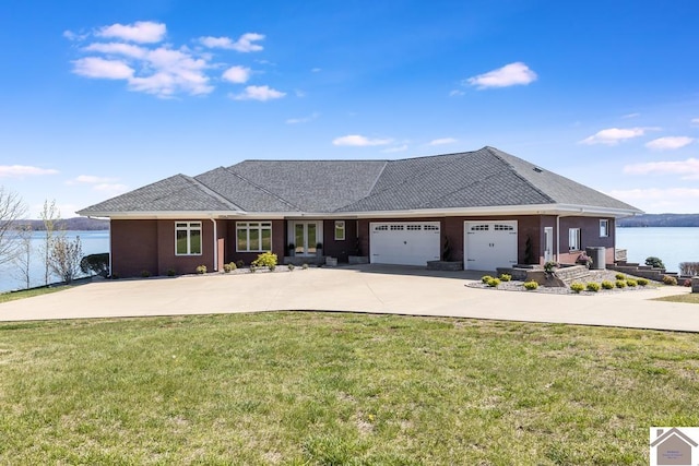 view of front of property featuring a garage, a water view, and a front lawn