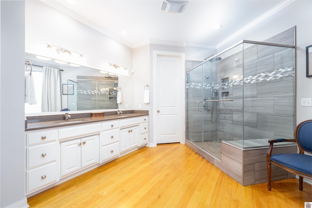 bathroom featuring dual bowl vanity, an enclosed shower, hardwood / wood-style flooring, and crown molding