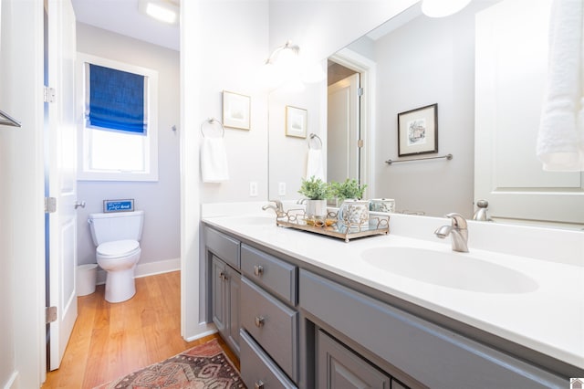 bathroom with oversized vanity, dual sinks, toilet, and hardwood / wood-style flooring