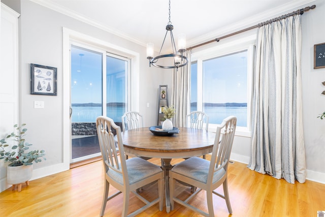 dining space featuring ornamental molding, light hardwood / wood-style floors, a water view, and a chandelier