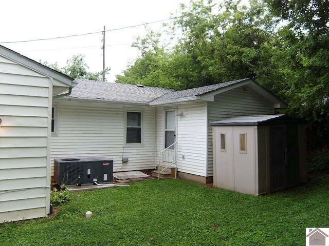 back of property with a yard, central AC, and a shed