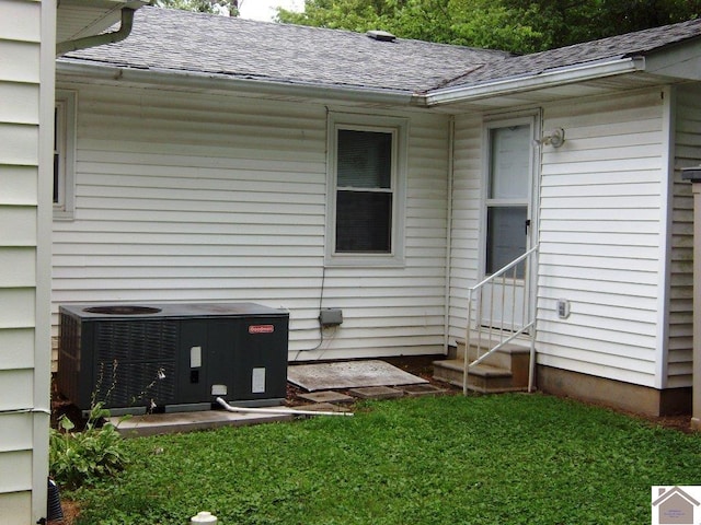 exterior space featuring central air condition unit and a yard