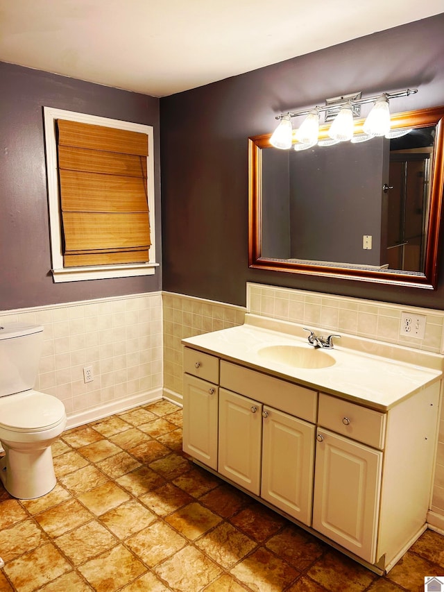 bathroom with vanity, toilet, and tile walls